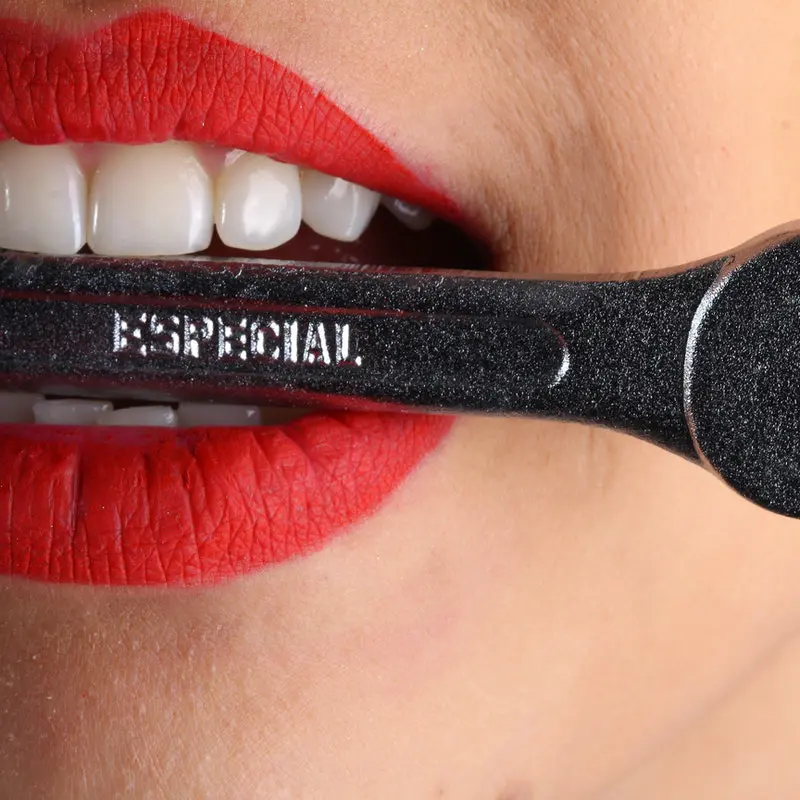 woman holding wrench in mouth with her straight teeth, signifying dental or Orofacial Myofunctional Therapy work