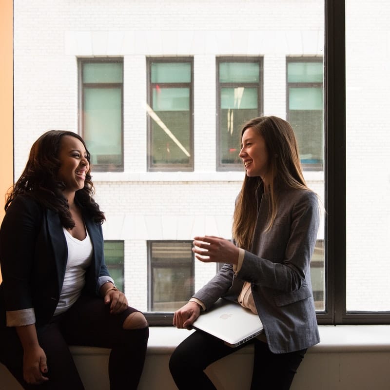 two women sitting on a ledge, one woman interviewing a student for a job