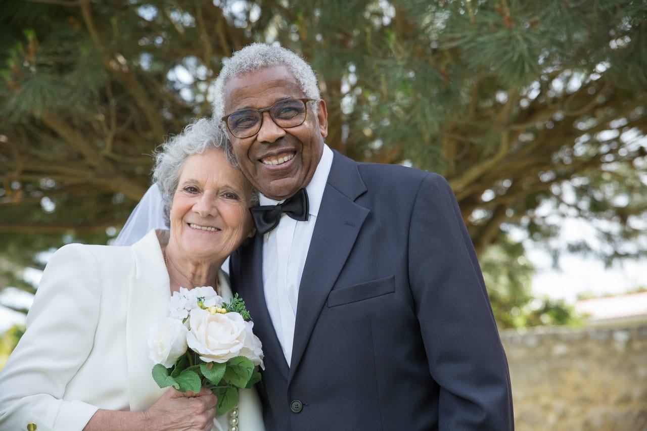 Senior interracial couple posing at their wedding, smiling.